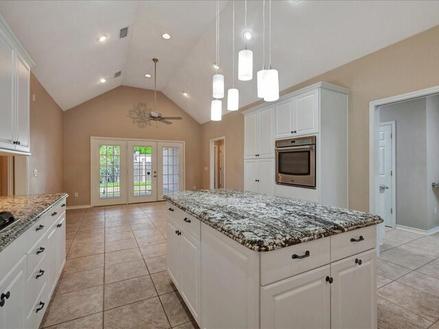 2601 Woodstock Dr, Lufkin, TX 75904 - kitchen with oven, a kitchen island, lofted ceiling, stone countertops, and light tile patterned flooring