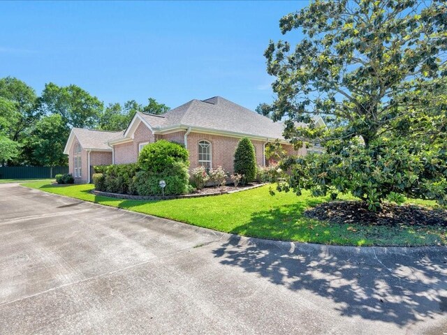 2601 Woodstock Dr, Lufkin, TX 75904 - view of property exterior featuring brick siding, a lawn, and a shingled roof