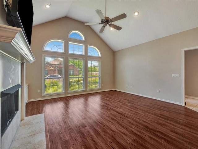 2601 Woodstock Dr, Lufkin, TX 75904 - unfurnished living room featuring a ceiling fan, light wood-style flooring, a fireplace with flush hearth, baseboards, and high vaulted ceiling