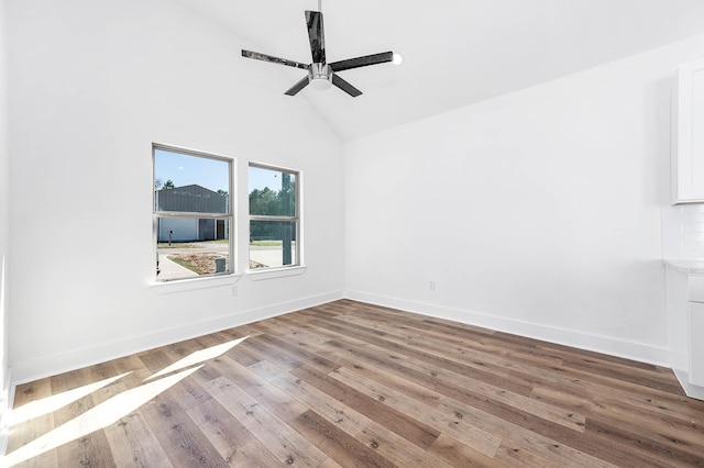 empty room featuring ceiling fan, high vaulted ceiling, hardwood / wood-style flooring, and baseboards