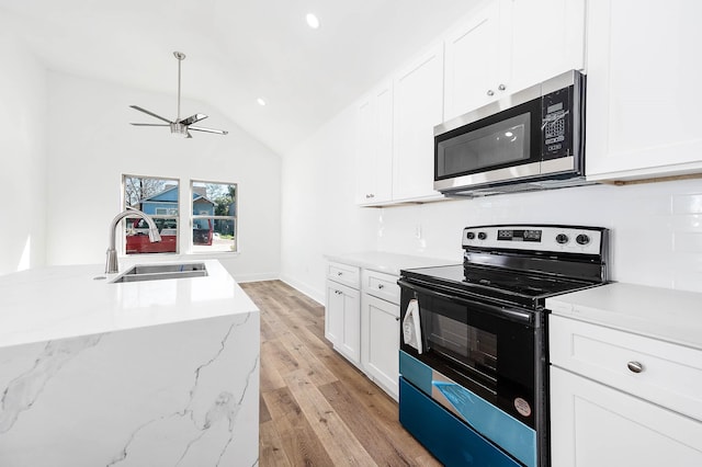 kitchen featuring light wood-style flooring, black range with electric stovetop, a sink, vaulted ceiling, and stainless steel microwave