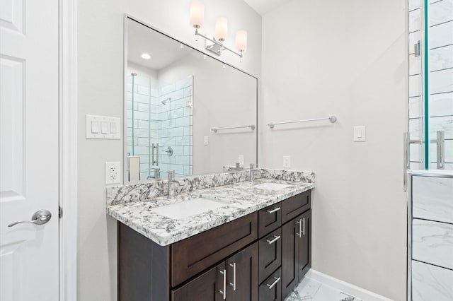 full bath with marble finish floor, baseboards, a sink, and a stall shower