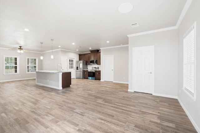 kitchen with appliances with stainless steel finishes, open floor plan, light countertops, dark brown cabinets, and a sink