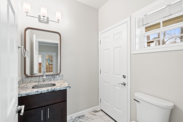 half bath with marble finish floor, vanity, toilet, and baseboards