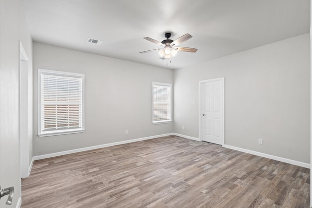 spare room featuring visible vents, ceiling fan, baseboards, and wood finished floors