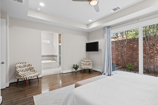 bedroom with hardwood / wood-style flooring, recessed lighting, visible vents, baseboards, and a raised ceiling