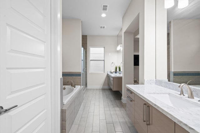 full bathroom with a stall shower, two vanities, a sink, and visible vents