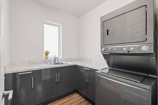 washroom featuring a sink, light wood finished floors, cabinet space, and stacked washer / drying machine