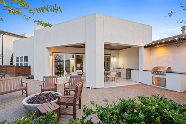 rear view of property with an outdoor fire pit, a patio, exterior kitchen, and stucco siding