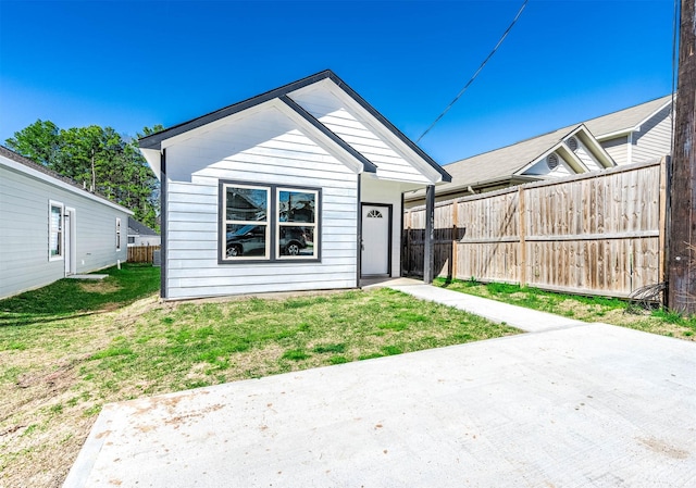 view of front of house with a front lawn, a patio area, and fence