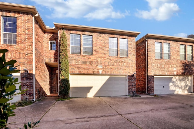 view of property featuring a garage, concrete driveway, and brick siding