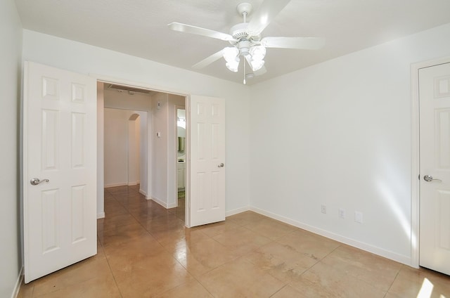 spare room featuring a ceiling fan, arched walkways, baseboards, and light tile patterned floors