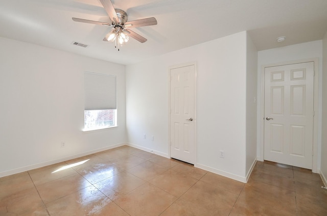 spare room featuring a ceiling fan, visible vents, baseboards, and light tile patterned floors