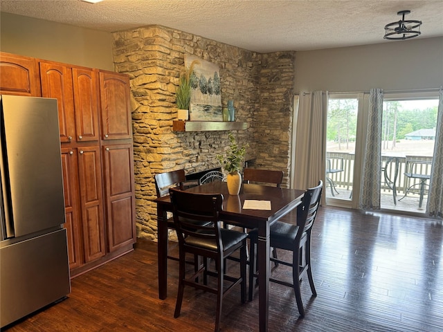 dining space featuring a textured ceiling, a fireplace, and dark wood-style flooring