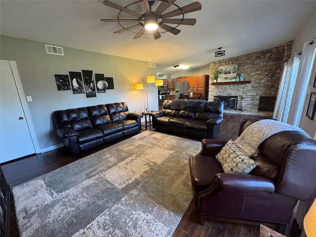 living room with visible vents, a ceiling fan, wood finished floors, a textured ceiling, and a fireplace