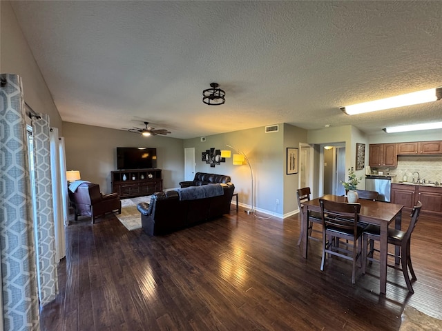 living room featuring baseboards, visible vents, dark wood-style floors, ceiling fan, and a textured ceiling