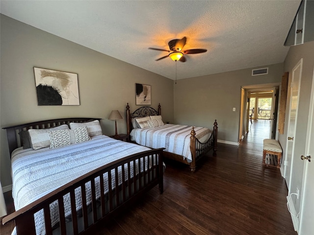 bedroom with lofted ceiling, a textured ceiling, visible vents, and wood finished floors