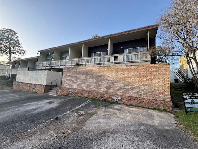 view of front of property featuring crawl space, uncovered parking, and brick siding