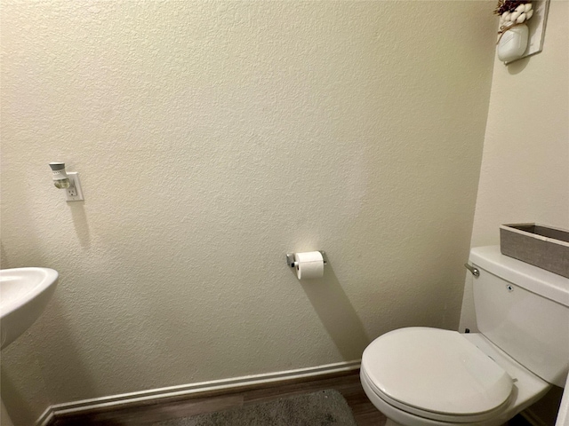 bathroom featuring toilet, baseboards, and a textured wall