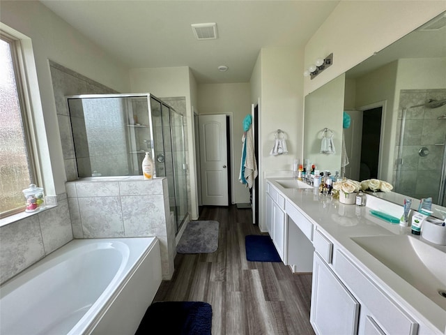 bathroom with a bath, a stall shower, a sink, and visible vents