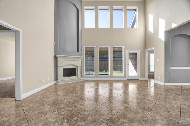 unfurnished living room with tile patterned flooring, a fireplace, baseboards, and a wealth of natural light