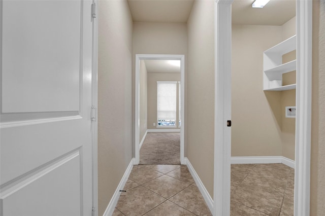 hallway with light tile patterned floors and baseboards