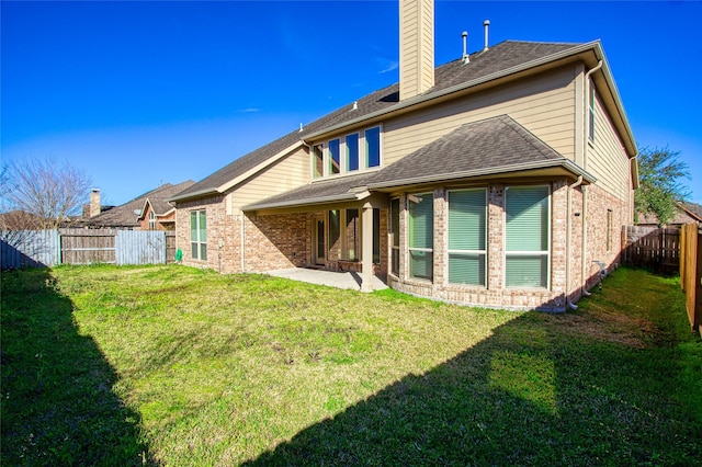 back of property with a fenced backyard, brick siding, a lawn, a chimney, and a patio area