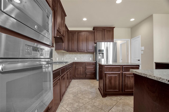 kitchen featuring light tile patterned floors, recessed lighting, backsplash, appliances with stainless steel finishes, and light stone countertops