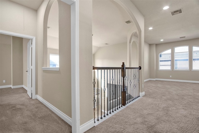 corridor with carpet floors, visible vents, and baseboards