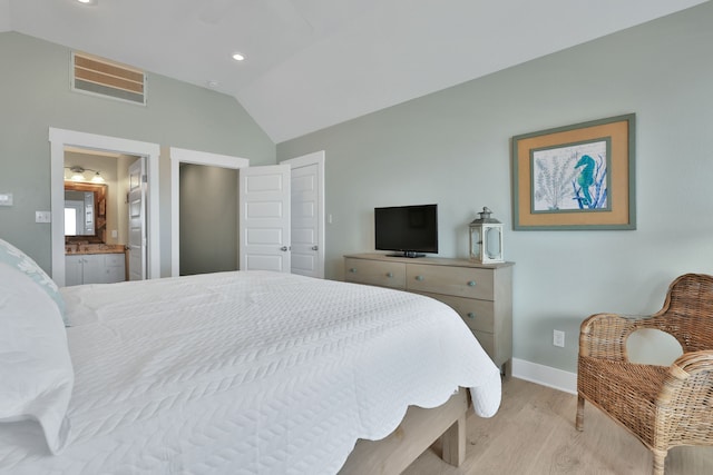 bedroom featuring baseboards, visible vents, lofted ceiling, wood finished floors, and ensuite bathroom