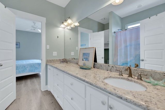 full bathroom with double vanity, a ceiling fan, a sink, and wood finished floors