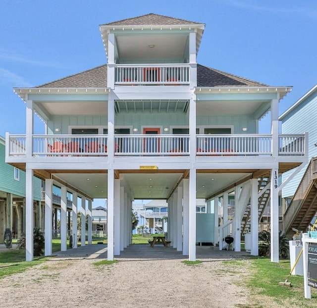 1319 Emerald Dr, Crystal Beach, TX 77650 - coastal inspired home featuring a carport, roof with shingles, board and batten siding, and dirt driveway