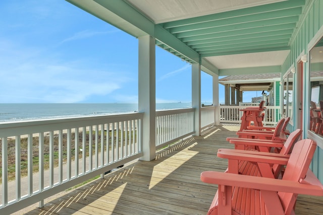 wooden terrace featuring a water view and a beach view