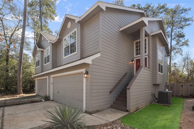 view of side of home with driveway, fence, a garage, and central AC