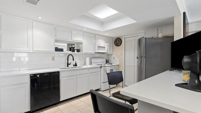 kitchen featuring light tile patterned floors, white appliances, a sink, white cabinets, and decorative backsplash