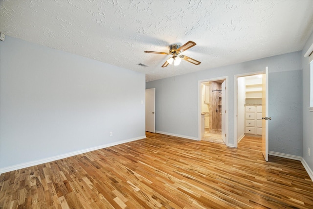 unfurnished bedroom featuring visible vents, a textured ceiling, baseboards, and light wood-style floors