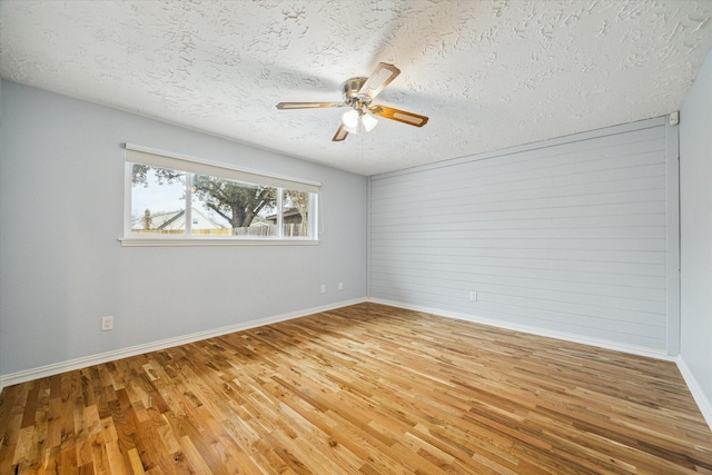 spare room with baseboards, a textured ceiling, wood finished floors, and a ceiling fan