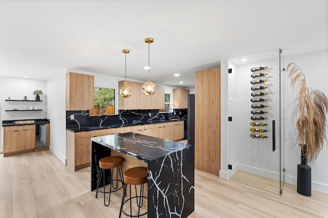 kitchen with light wood-type flooring, modern cabinets, and a kitchen bar