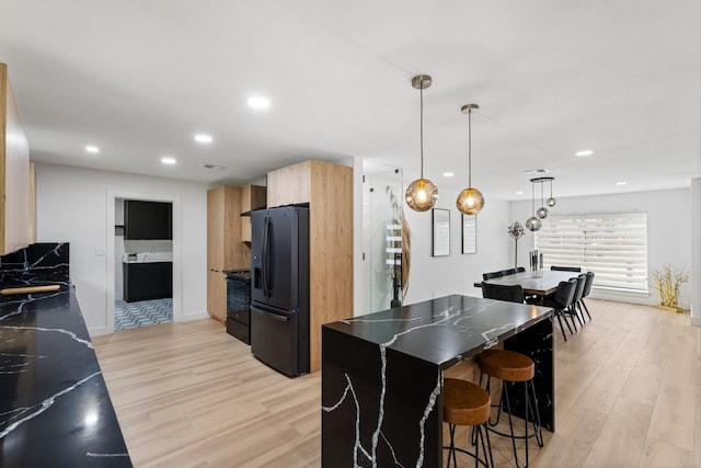 kitchen featuring black refrigerator with ice dispenser, stove, modern cabinets, and light wood-style floors