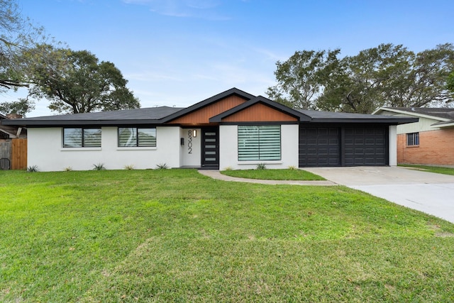 view of front of home featuring a garage, concrete driveway, a front yard, and stucco siding