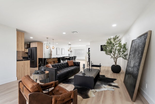 living room with light wood finished floors, visible vents, and recessed lighting