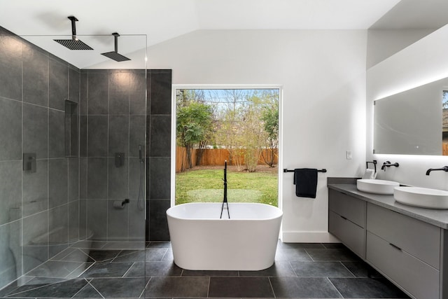 bathroom featuring a stall shower, a freestanding bath, vaulted ceiling, and a sink