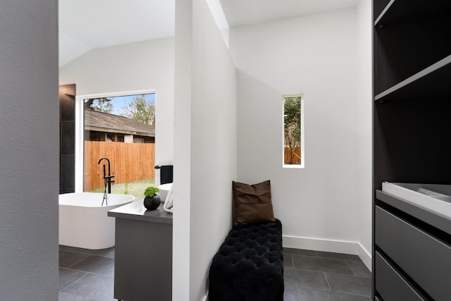 interior space with vaulted ceiling, dark tile patterned floors, and baseboards