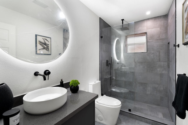 bathroom with toilet, visible vents, a tile shower, and vanity