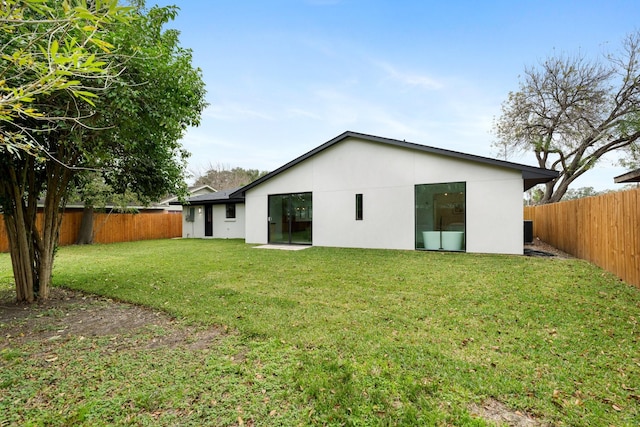 rear view of property with a yard and a fenced backyard