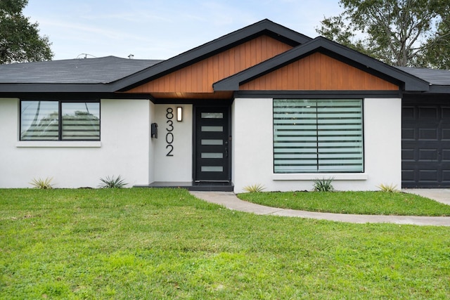 view of front facade featuring an attached garage, stucco siding, and a front yard