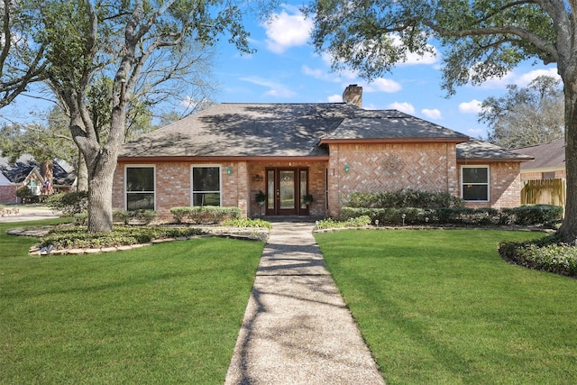 view of front facade featuring brick siding, fence, a chimney, and a front lawn