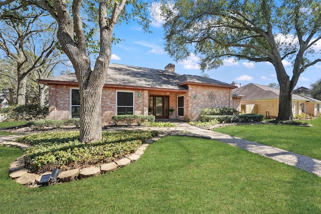 ranch-style home featuring a front yard, brick siding, and a chimney