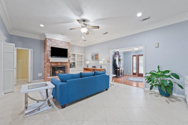 living area with light tile patterned floors, visible vents, ornamental molding, a textured ceiling, and a brick fireplace