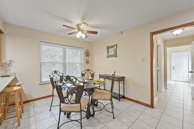 dining area featuring light tile patterned floors, a textured ceiling, a ceiling fan, and baseboards